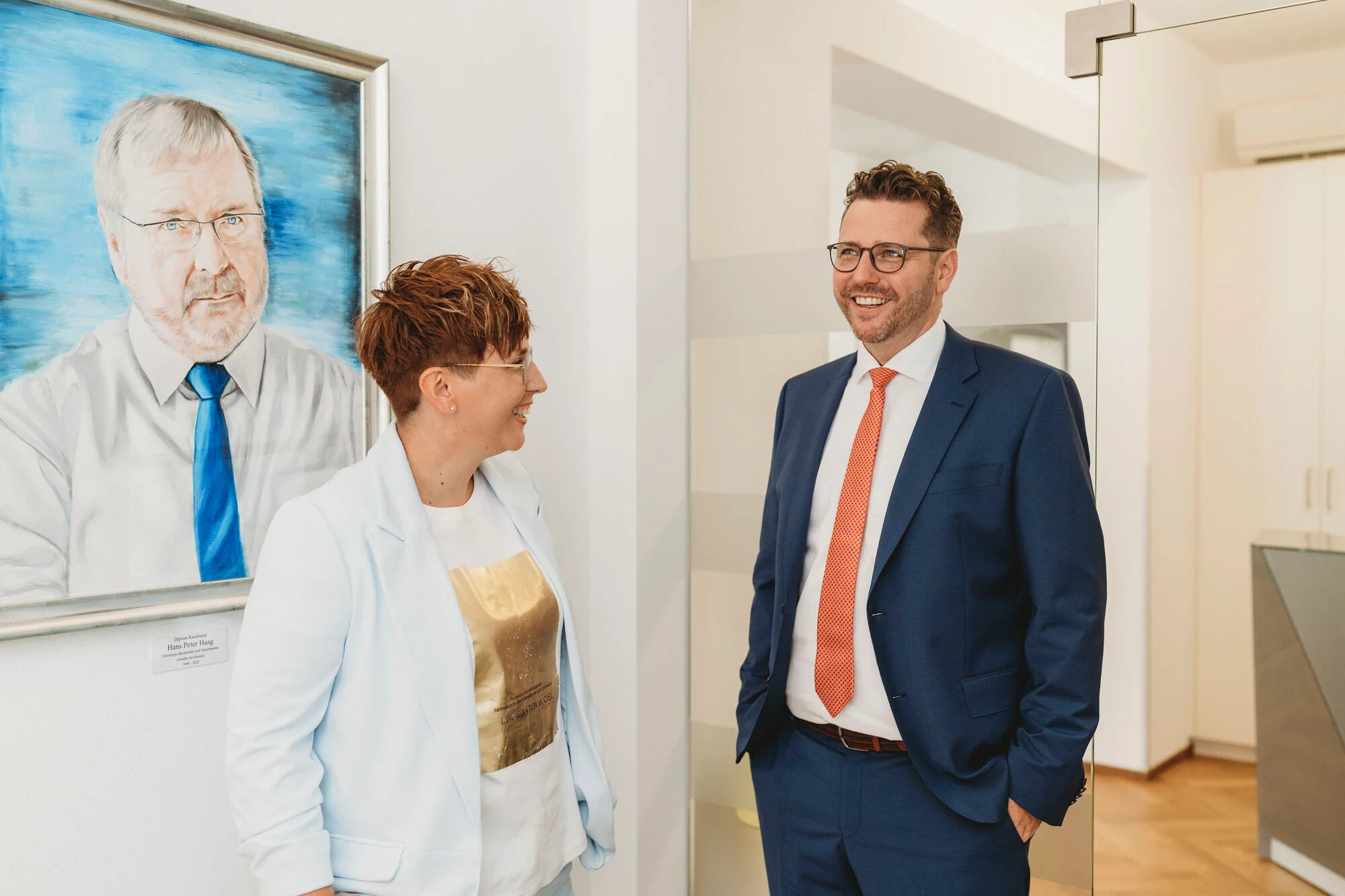 Marie Haag-Breiler und Dominik Haag mit dem Portrait des Gründers der Kanzlei Haag