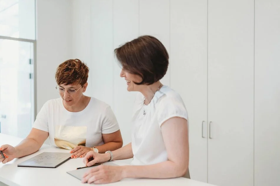 Frauen stehen vor Dokumenten und schauen diese an